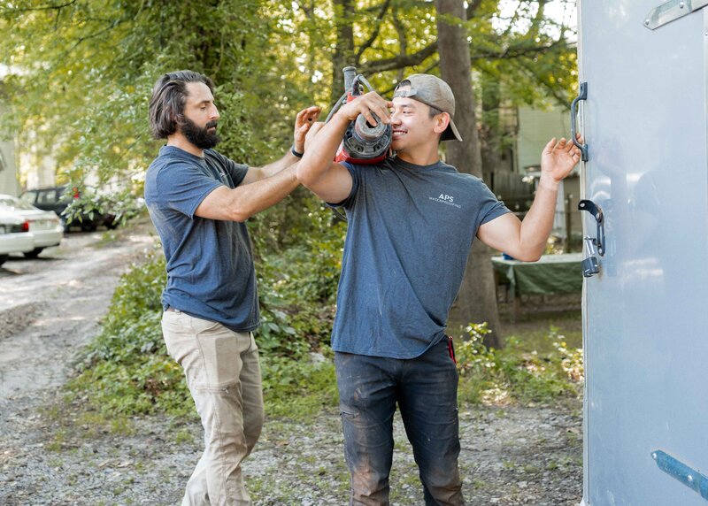 One man helping another man carry equipment for Atlanta waterproofing services
