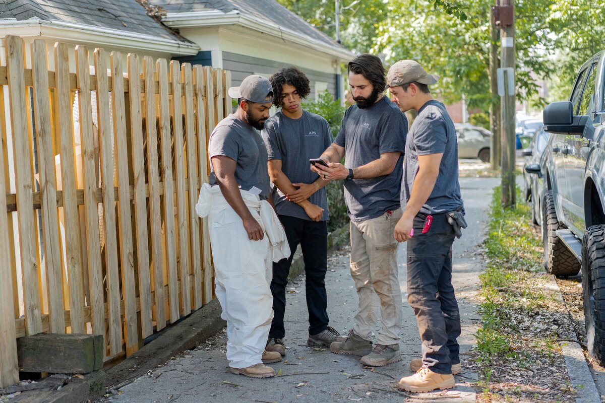 Four men standing and discussing plans for Atlanta waterproofing services